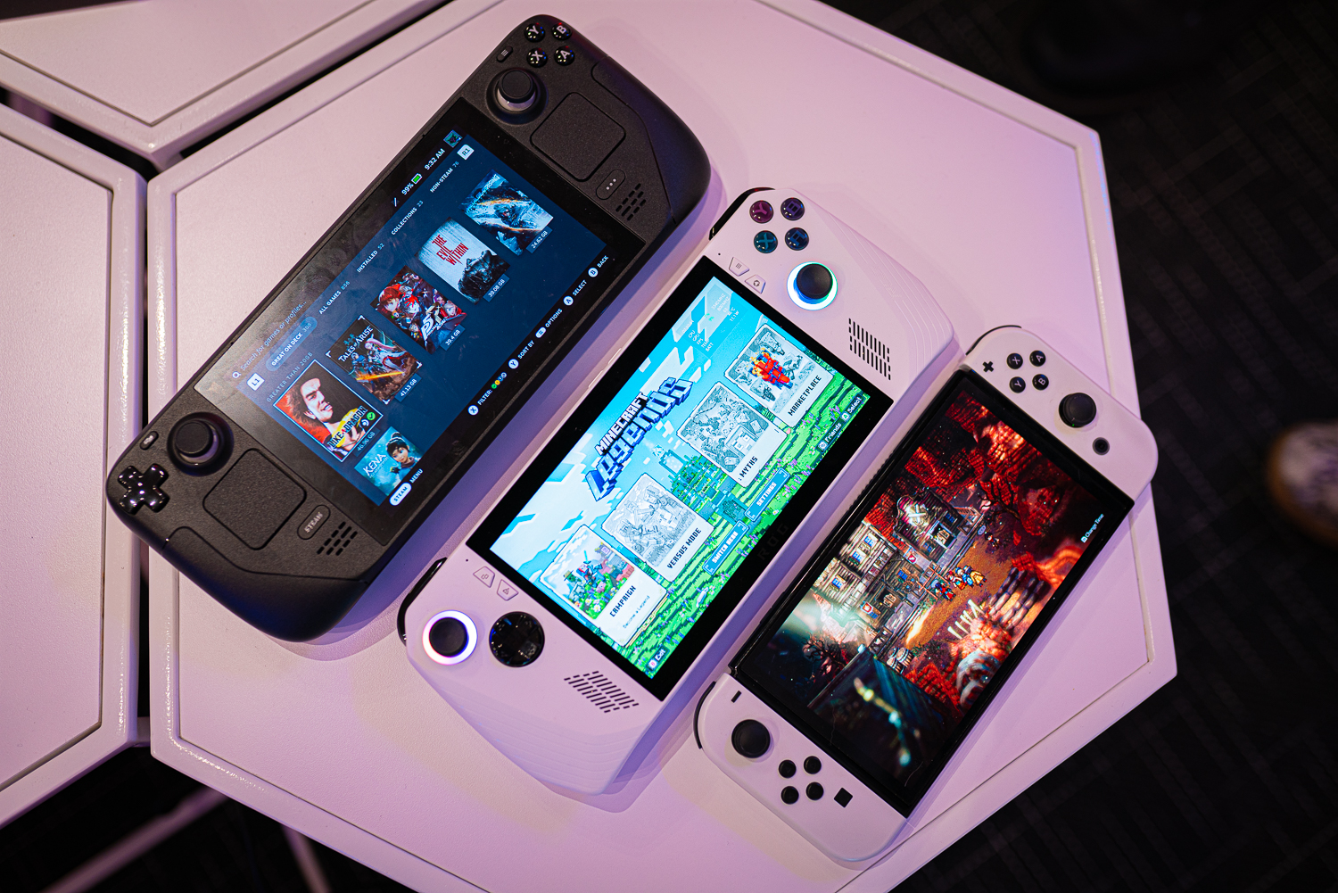 A Steam Deck, Asus ROG Ally, and Nintendo Switch OLED sit on a table.