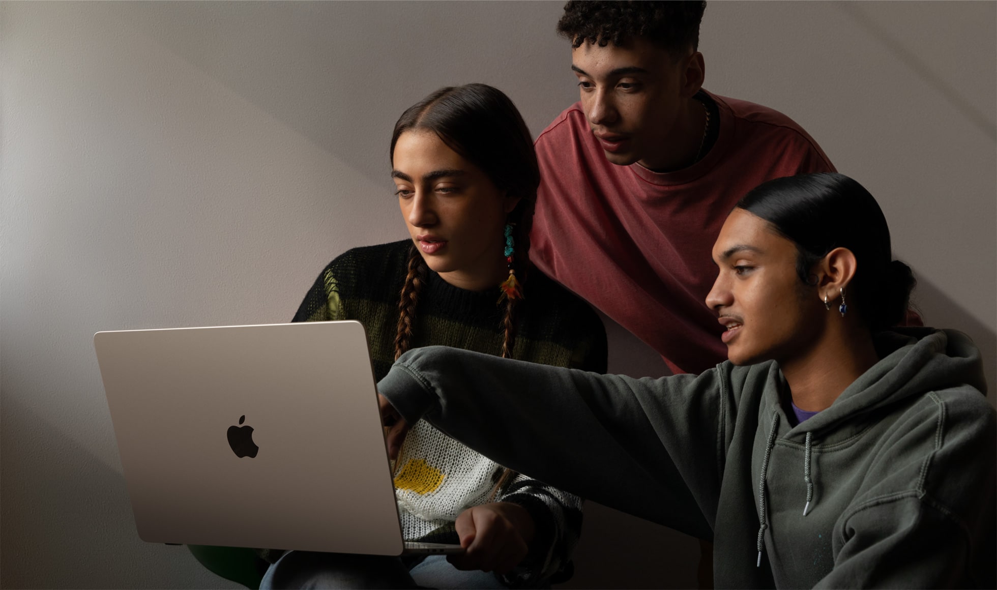 Three people sit in front of a 15-inch MacBook Air, which is seen from the back.
