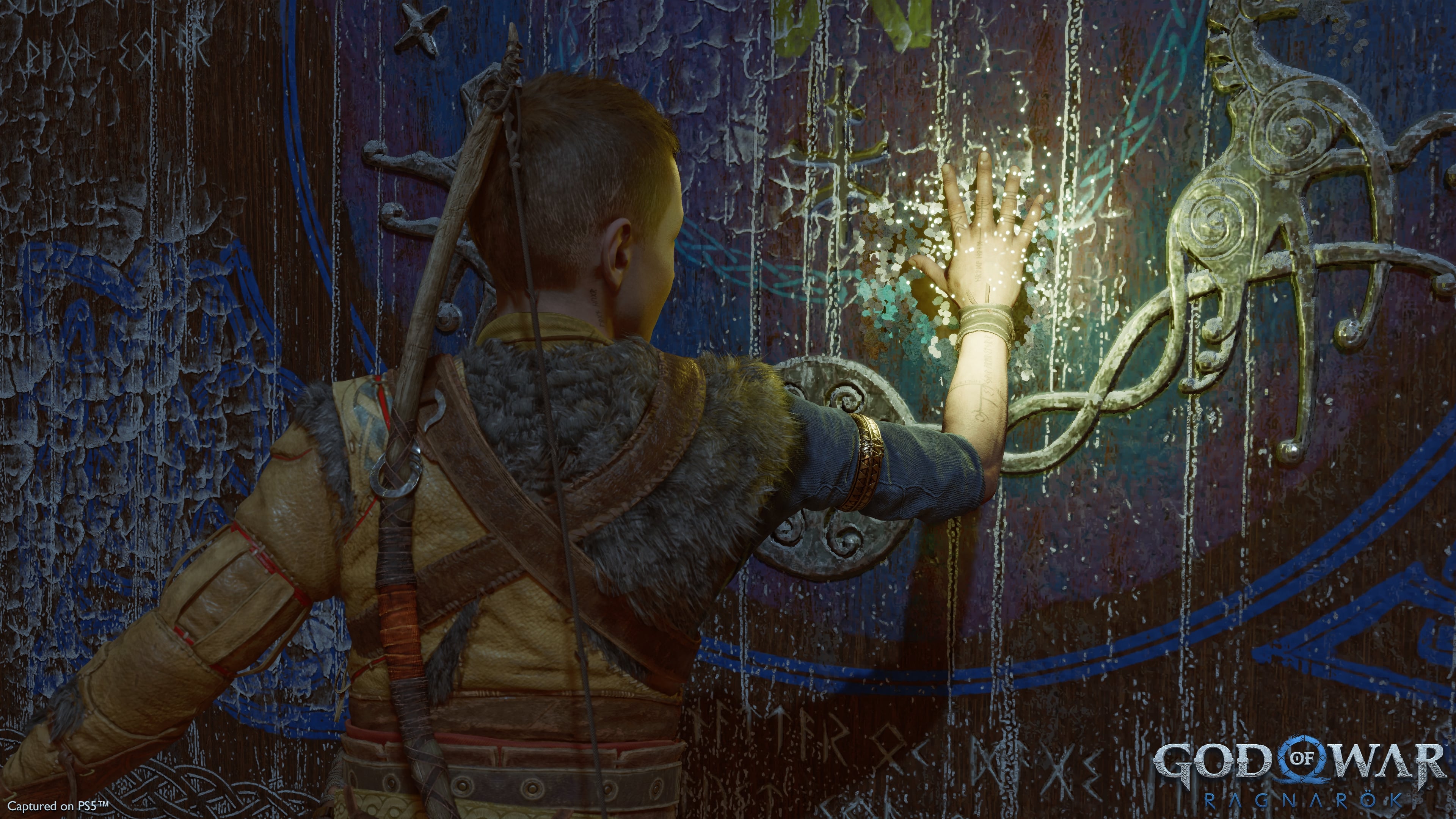 God of War Ragnarok Atreus touching a mural.