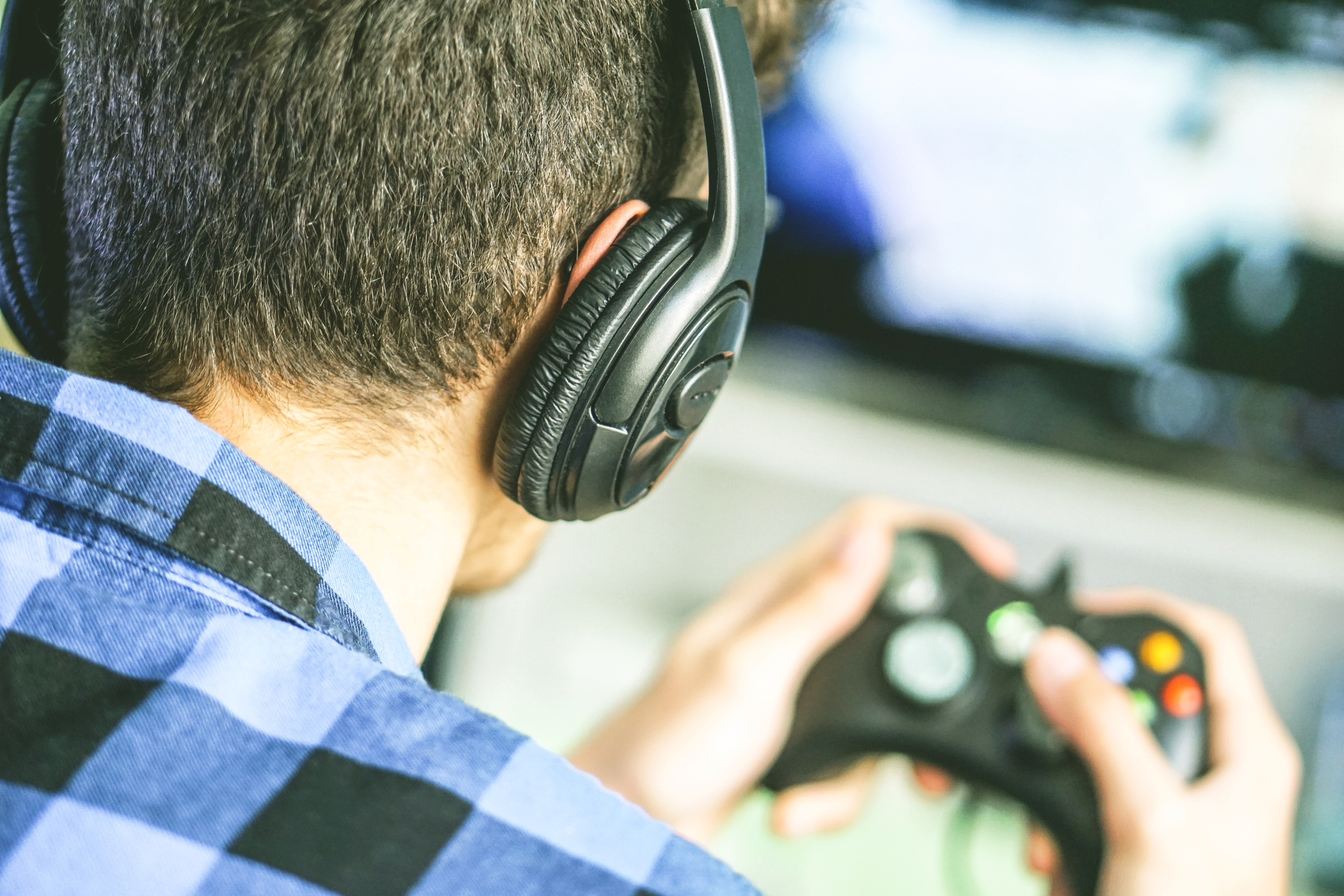 Gamer playing Xbox One with headset on.
