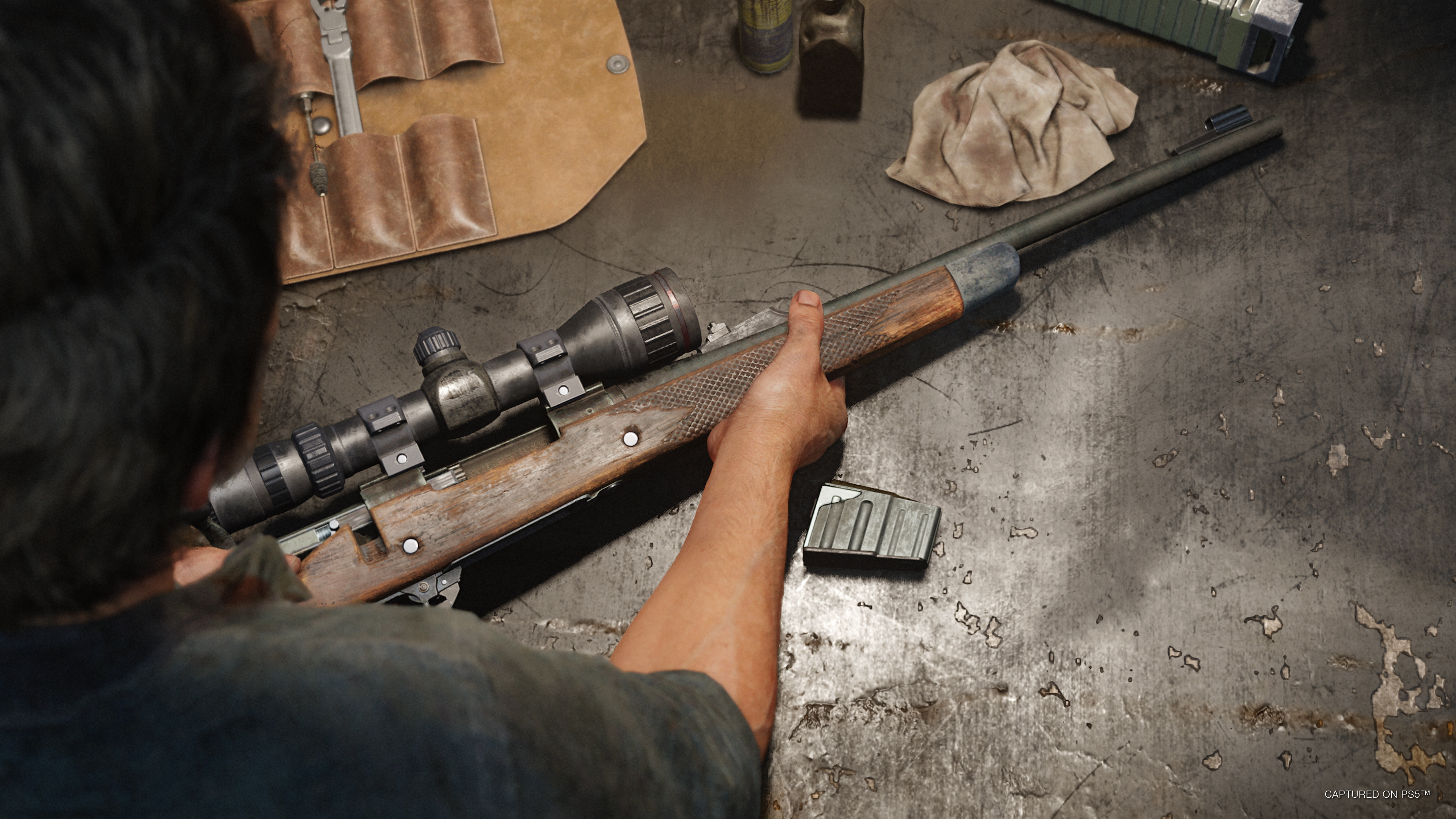 Joel places a rifle on a table in The Last of Us Part I.
